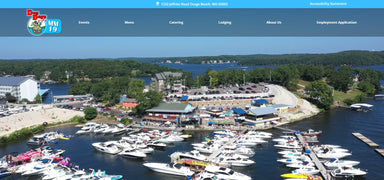 Marina with boats docked along a waterfront, surrounded by trees and buildings.